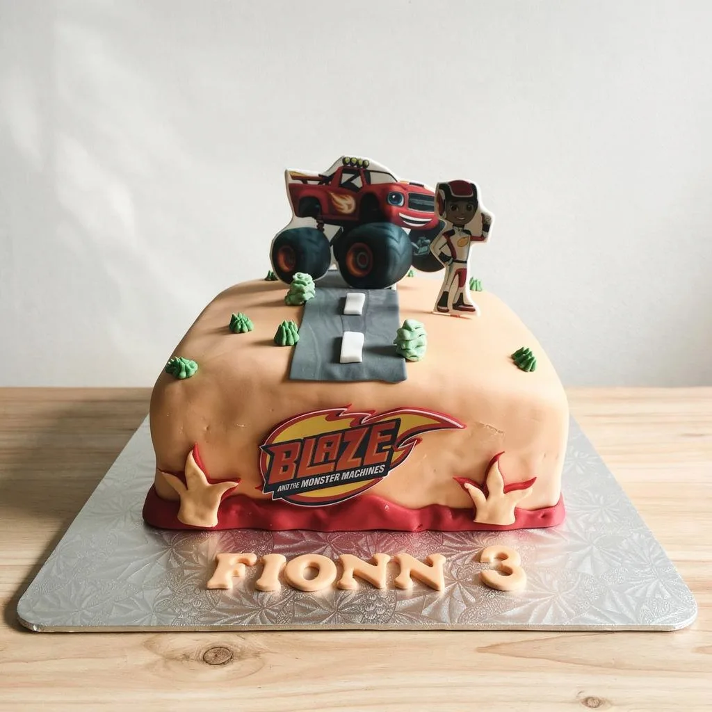 Rectangular cake with tan fondant decorated with Blaze and a character on a road with green bushes