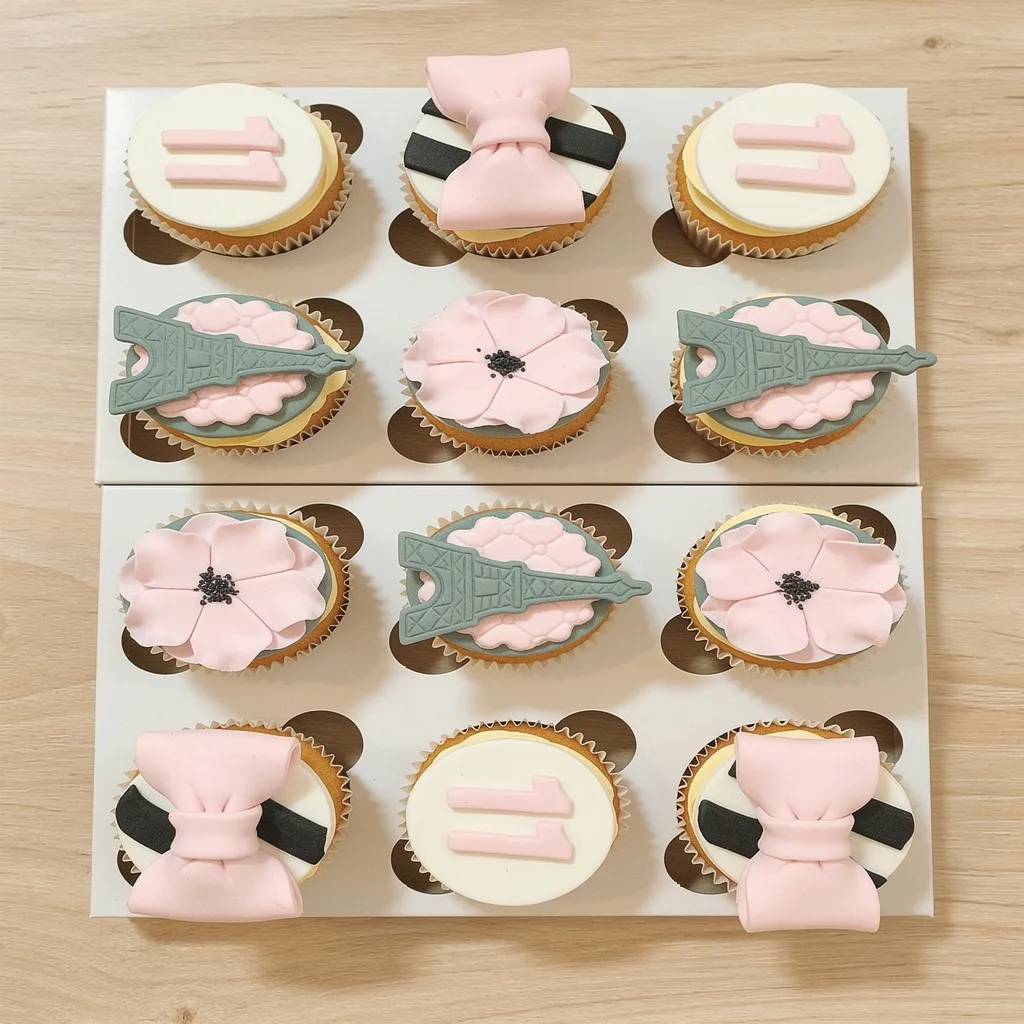 Set of twelve cupcakes with pink bows, Eiffel Tower decorations, pink flowers, and number 11 toppers