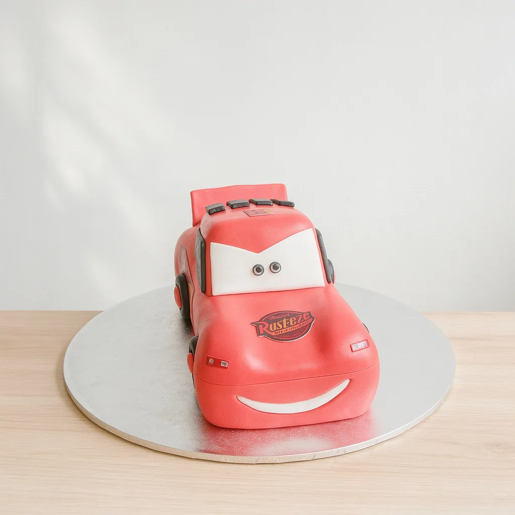 A red car-shaped cake with smiling face and eyes on the windshield